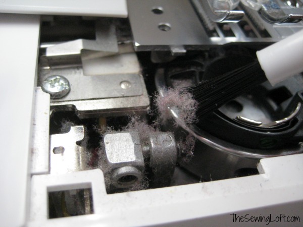 Cleaning and preparation of sewing machine. A woman uses a brush